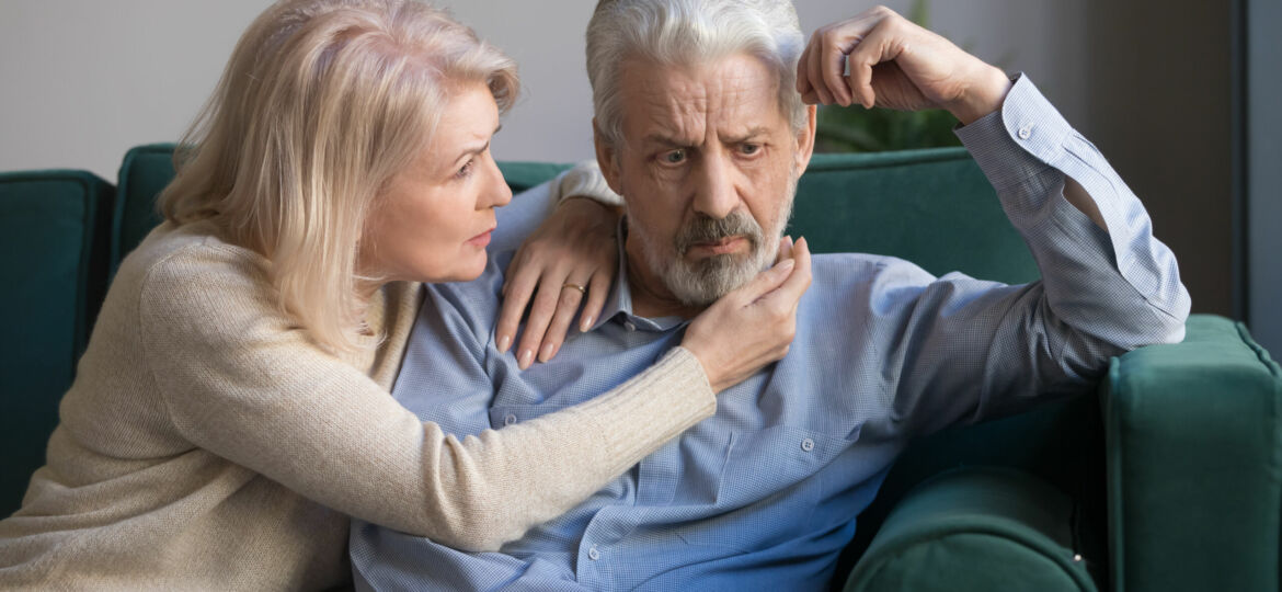 Middle aged wife comforting upset grey-haired husband